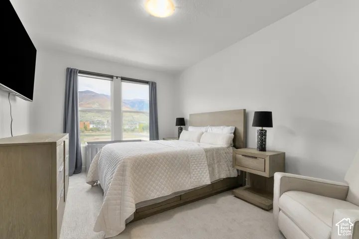 Bedroom featuring neutral carpeting, dual-pane windows, and a mountain backdrop