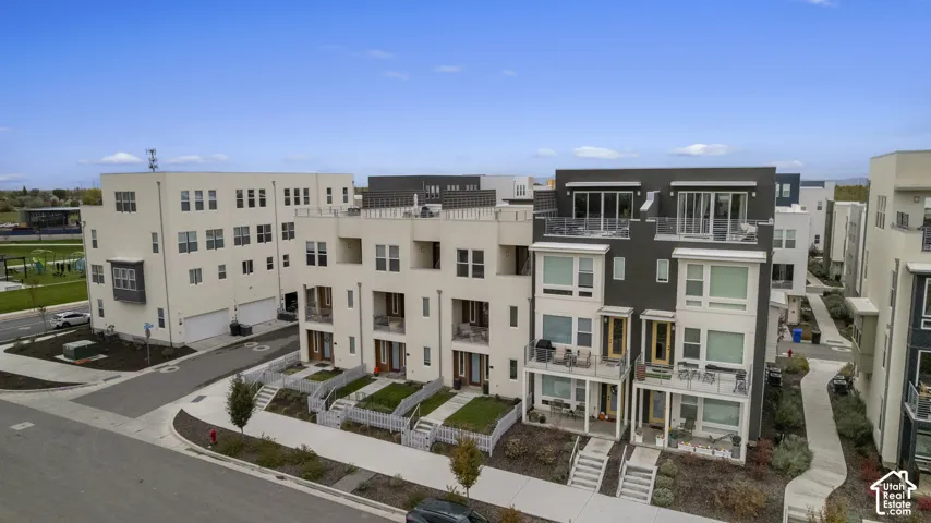 Multi-story residential exteriors featuring mixed stucco and panel siding, flat roof lines, glass-railed balconies, and fenced ground-level entryways
