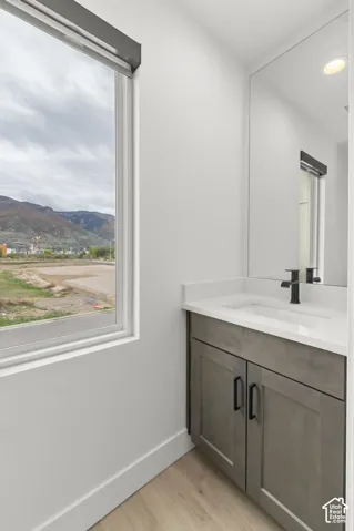 Vanity featuring gray cabinetry, matte black hardware, integrated rectangular sink, white countertop, and mountain backdrop