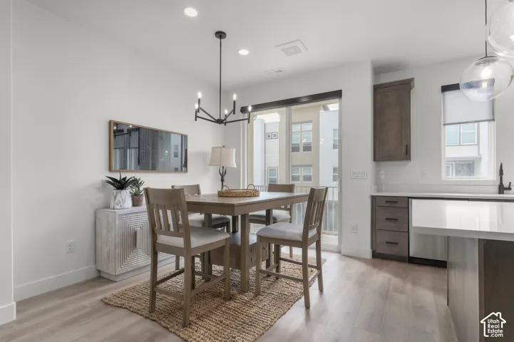 Dining area featuring wood-finish flooring, a modern multi-arm chandelier, and sliding glass doors