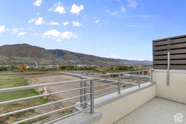 Outdoor balcony featuring metal railing, horizontal wood-slat privacy screen, concrete flooring, and mountainous backdrop