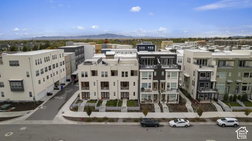 Multi-level townhome architecture featuring contemporary facades, private balconies, expansive windows, concrete-paved walkways, and mountain scenery