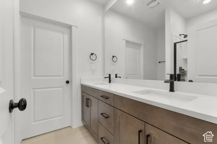 Double vanity with wood-finish cabinetry, quartz countertop, dual integrated rectangular sinks, and matte black fixtures