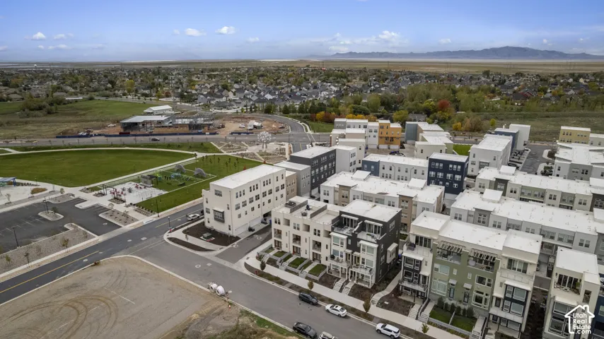 Aerial perspective of a multi-level residential development featuring contemporary architectural styling, integrated private balconies, attached garages, landscaped street-level grounds, and mountain range backdrop