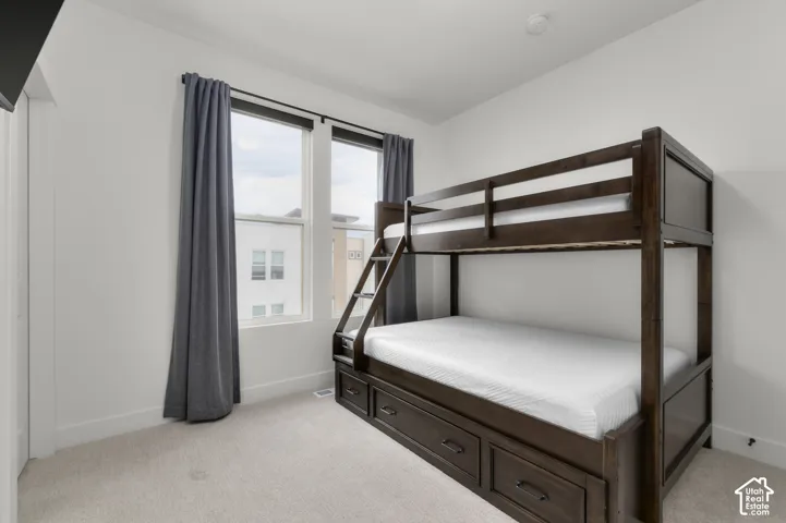 Neutral wall finishes, plush carpeting, and tall windows featuring dark-framed casings