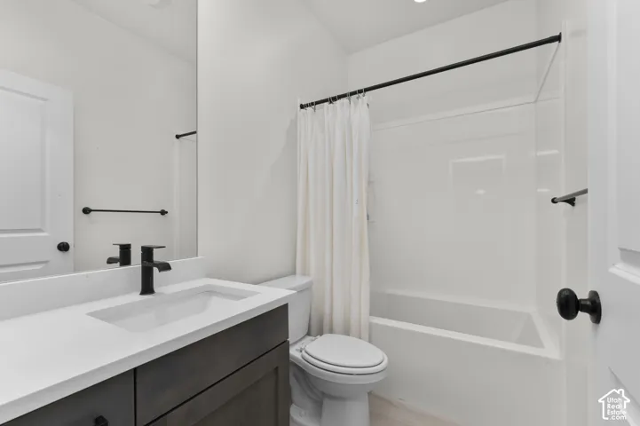 Bathroom featuring a dark wood-finish vanity, solid surface countertop with an integrated basin, matte black faucet and hardware, and a tub-shower combination with a surround