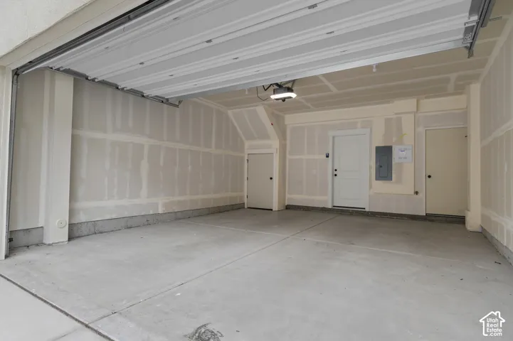 Multi-car garage featuring a concrete floor, overhead automatic door, and two interior access doors