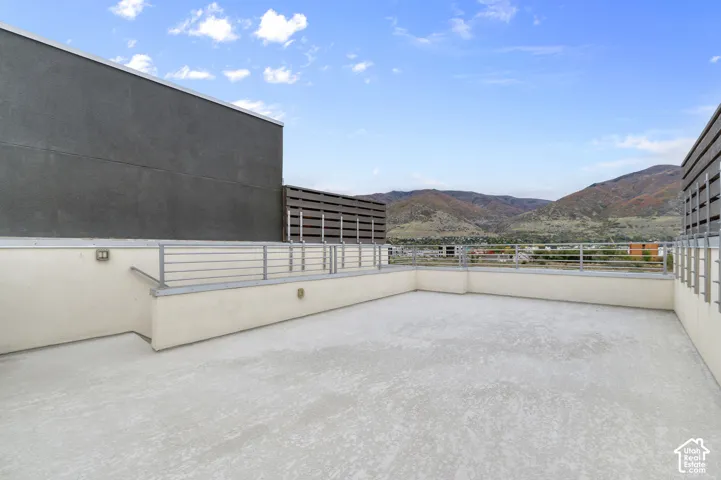 Rooftop terrace featuring concrete flooring, horizontal metal railing, privacy screens, and mountain scenery