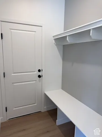 Built-in white storage bench with integrated shelving, wood-finish flooring, and solid-core door with matte black hardware