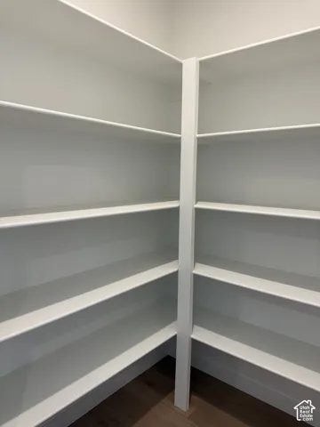 Custom corner shelving featuring tiered white built-in storage units and wood-finish flooring