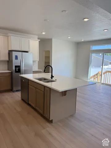 Kitchen featuring a central island with a solid surface countertop, wood-finish cabinetry, stainless steel appliances, recessed ceiling lighting, and wood-finish flooring