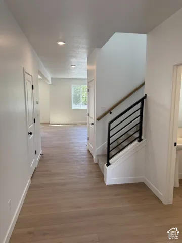 Staircase featuring a matte black metal railing and a wood-finish handrail, complemented by wide-plank wood-finish flooring and recessed lighting