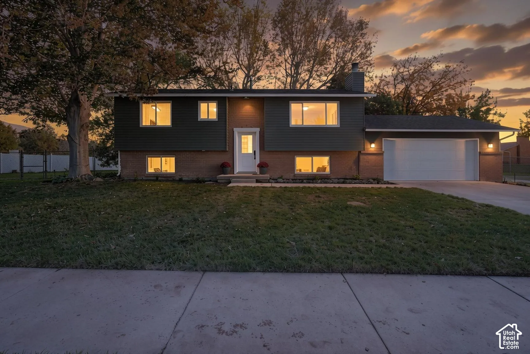 Split-level exterior featuring a brick and horizontal siding facade, attached two-car garage, concrete driveway, and mature landscaping