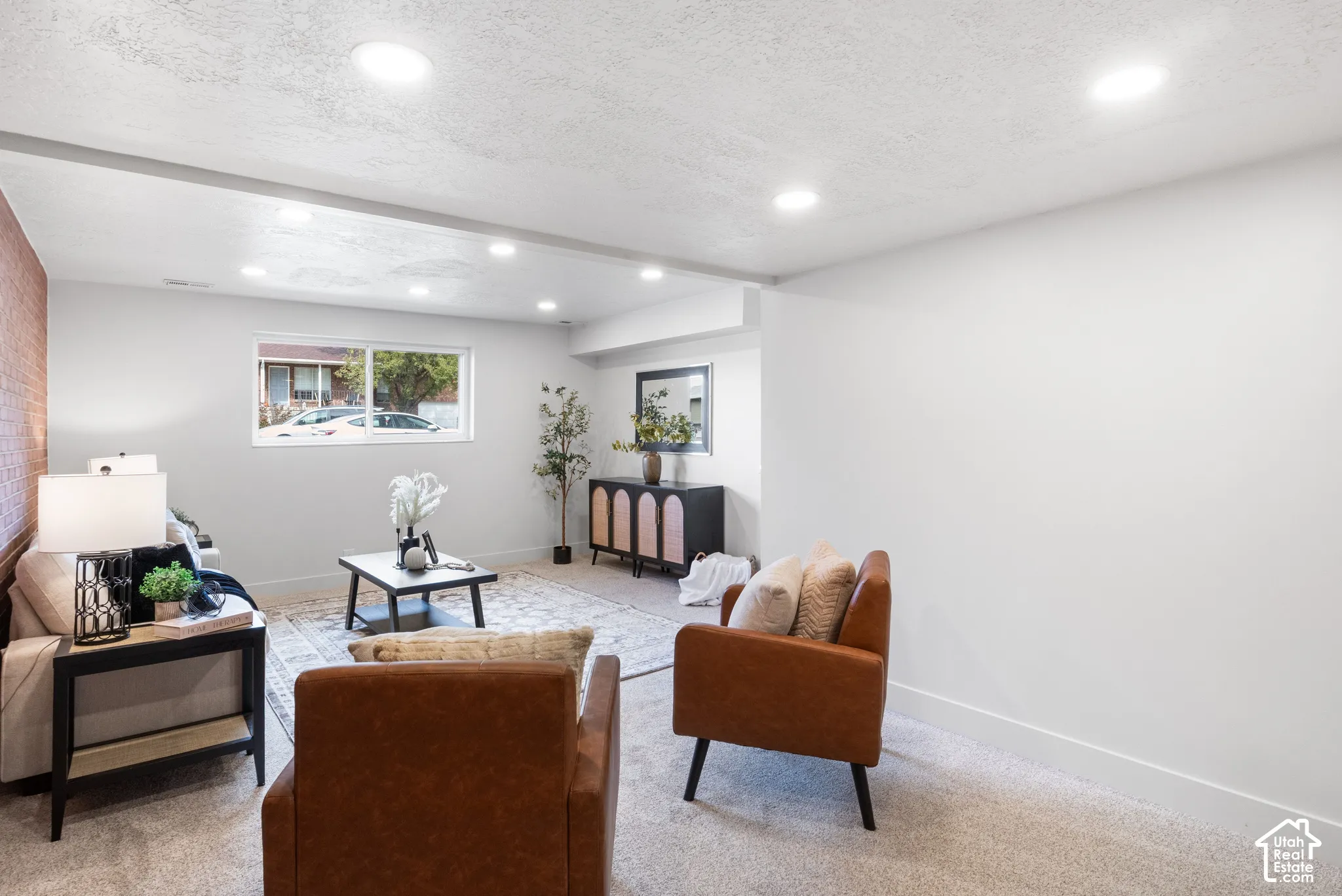 Interior space featuring neutral-toned carpeting, recessed ceiling lighting, a textured brick accent wall, and a horizontal window