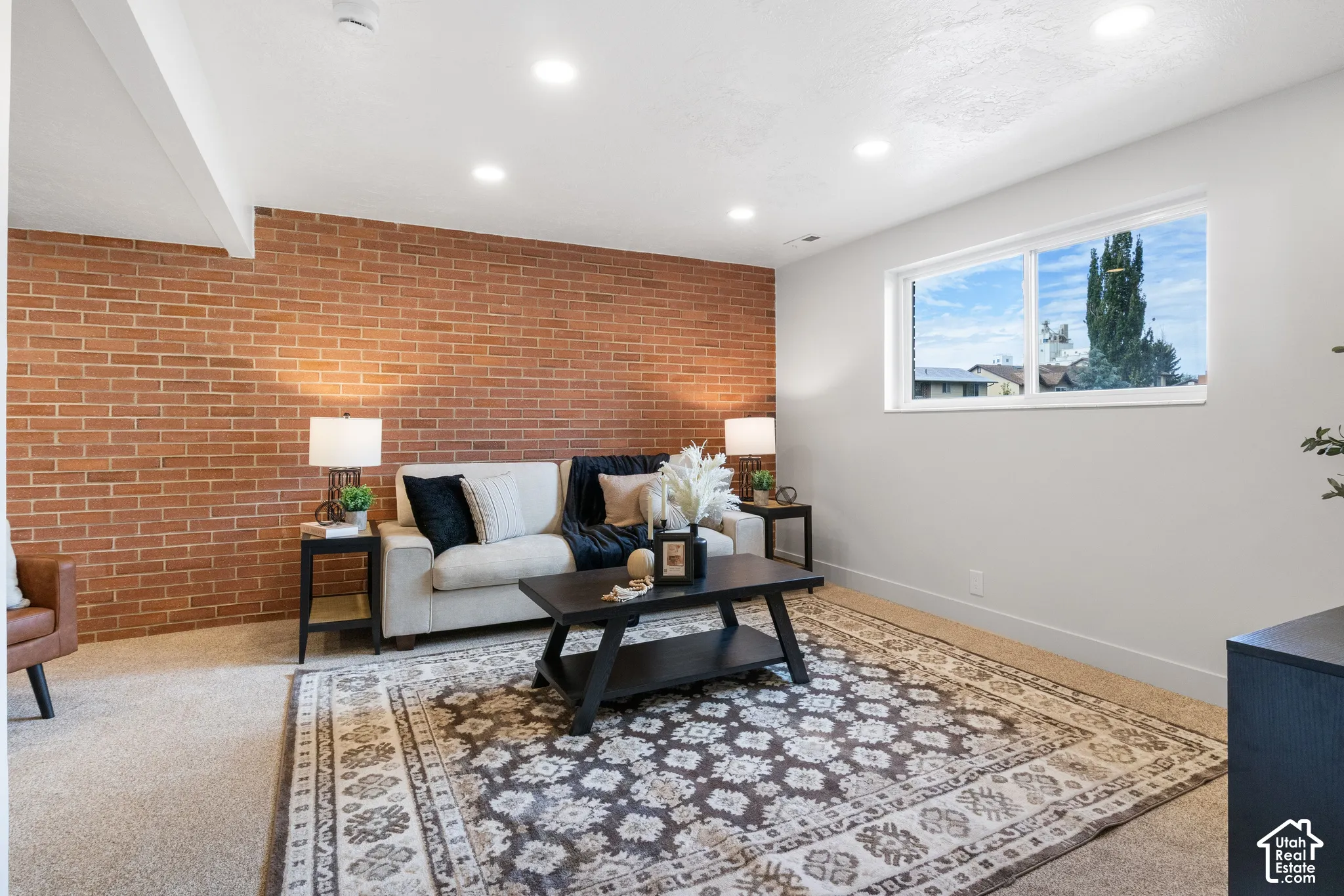 Exposed brick accent wall featuring recessed ceiling lighting and a large sliding window
