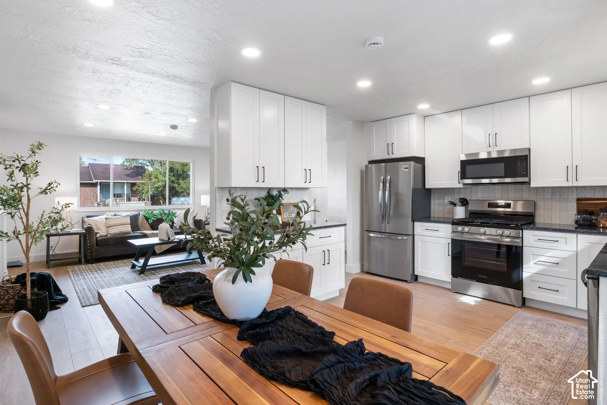 Kitchen featuring white shaker cabinetry, stainless steel appliances, dark countertops, recessed lighting, and wood-finish flooring