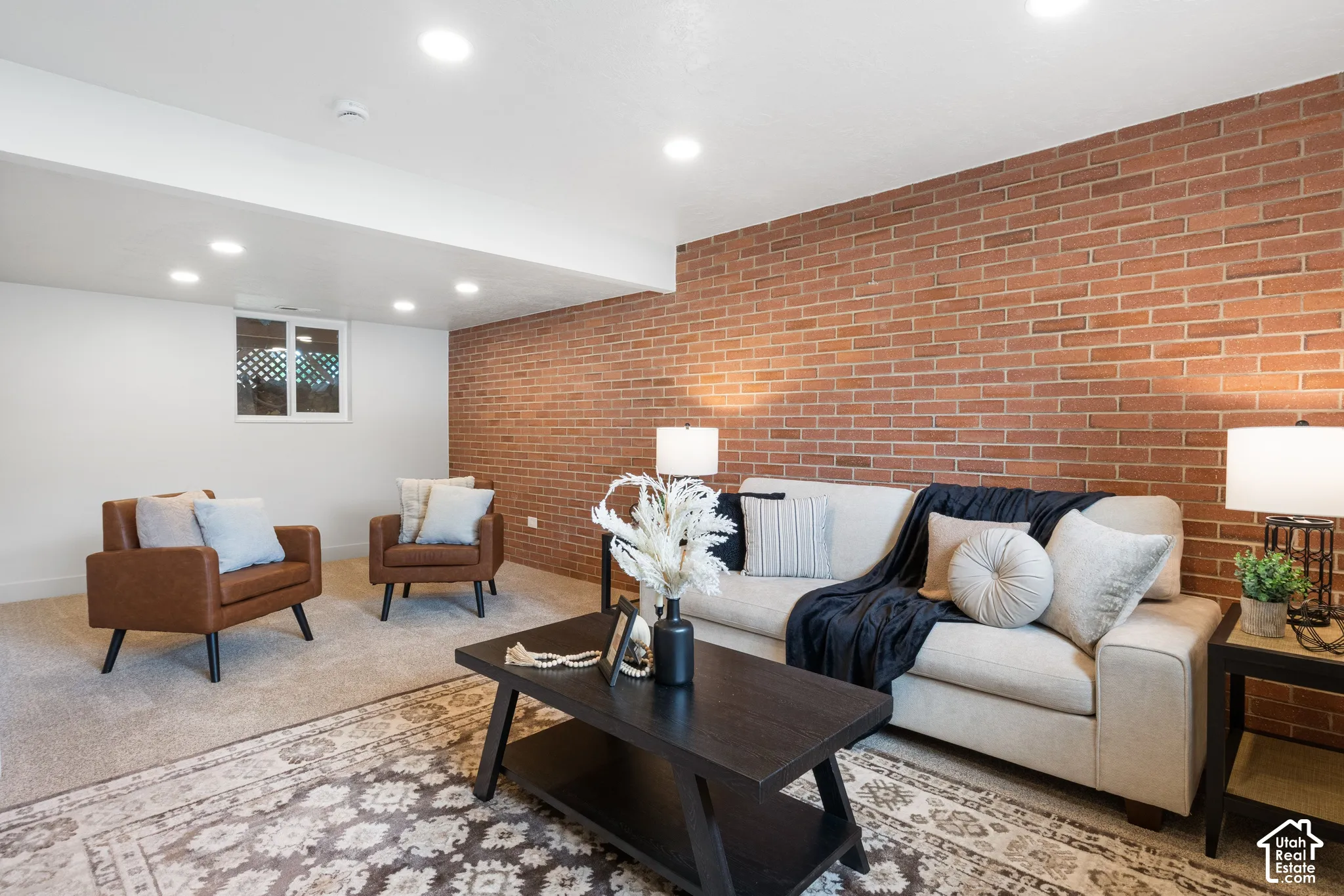 Exposed red brick accent wall, recessed lighting, and carpeted flooring