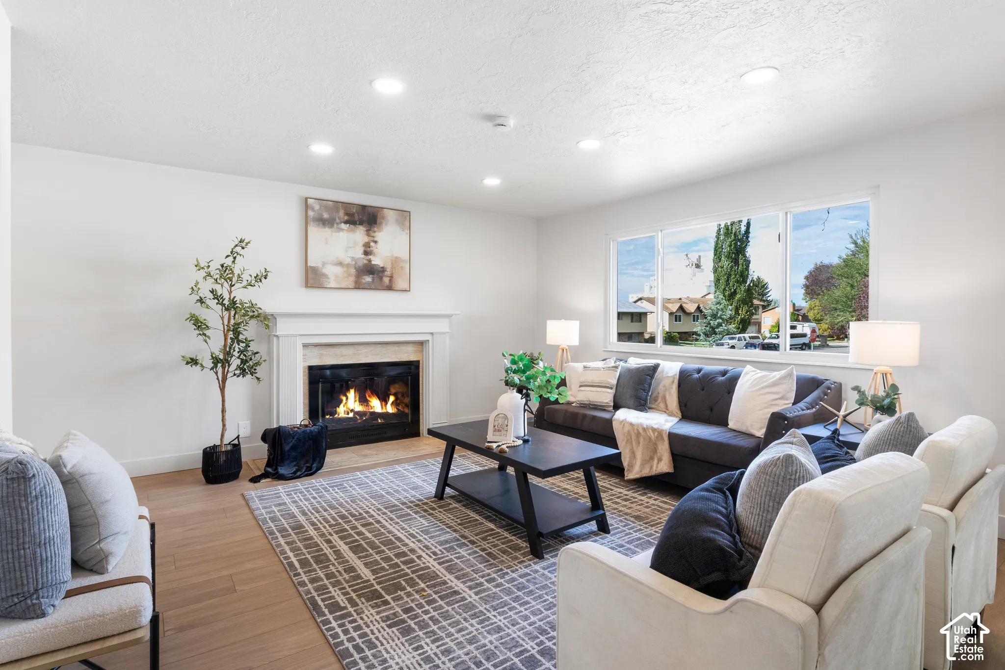 Living area featuring wood-finish flooring, recessed lighting, and a fireplace with a mantel surround