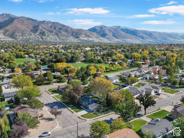 Aerial perspective of residential neighborhood featuring mature trees, landscaped lawns, and prominent mountain range backdrop