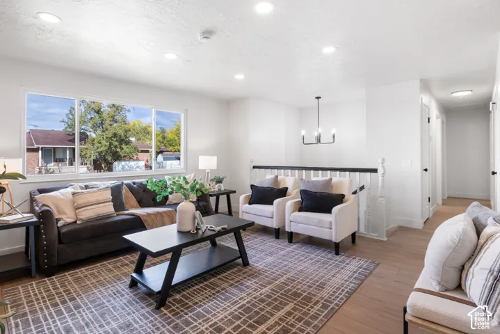 Living area featuring recessed lighting, wood-finish flooring, a large picture window, and a chandelier