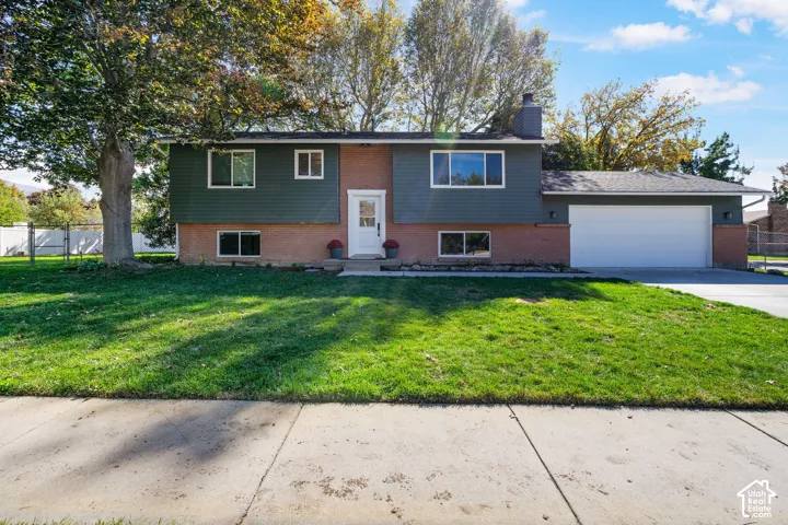 Split-level exterior featuring a brick and horizontal siding facade, attached two-car garage, and manicured front lawn