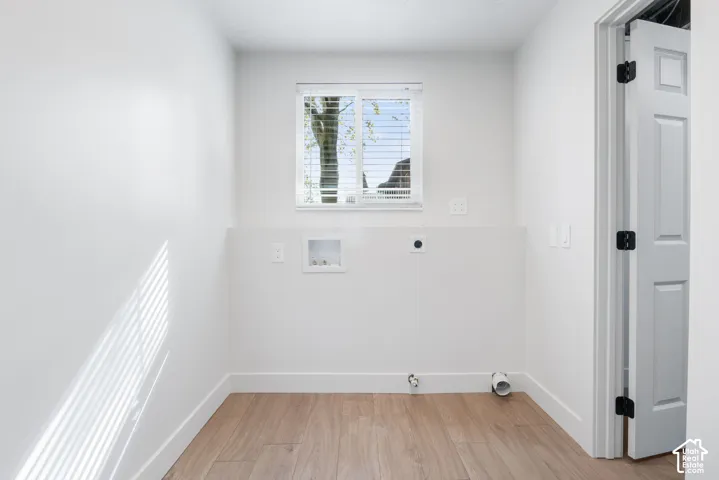 Utility area featuring wood-finish flooring, a single-pane sliding window, and a white paneled door
