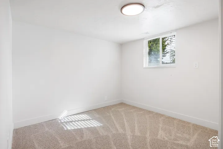 Neutral-toned wall-to-wall carpeting, crisp white walls, and a recessed ceiling light fixture, featuring a sliding window with horizontal blinds