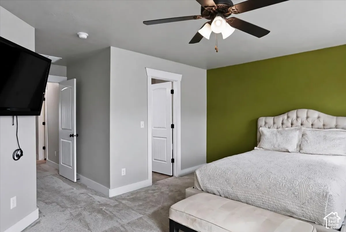 Primary Suite featuring neutral wall paint, a vibrant accent wall, wall-to-wall carpeting, and a ceiling fan with integrated lighting