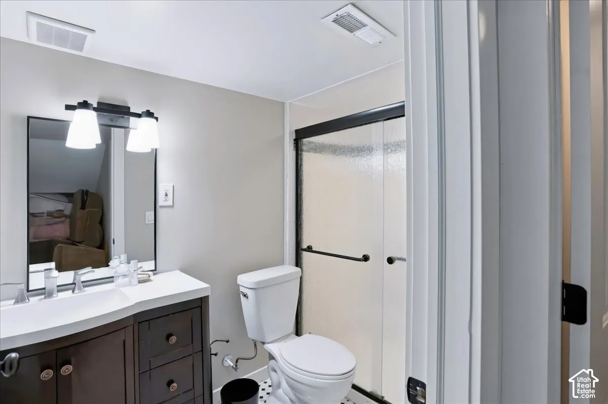 Bathroom featuring a dark wood-finish vanity with an integrated basin, framed rectangular mirror, two-light wall fixture, and a shower enclosure with sliding glass doors
