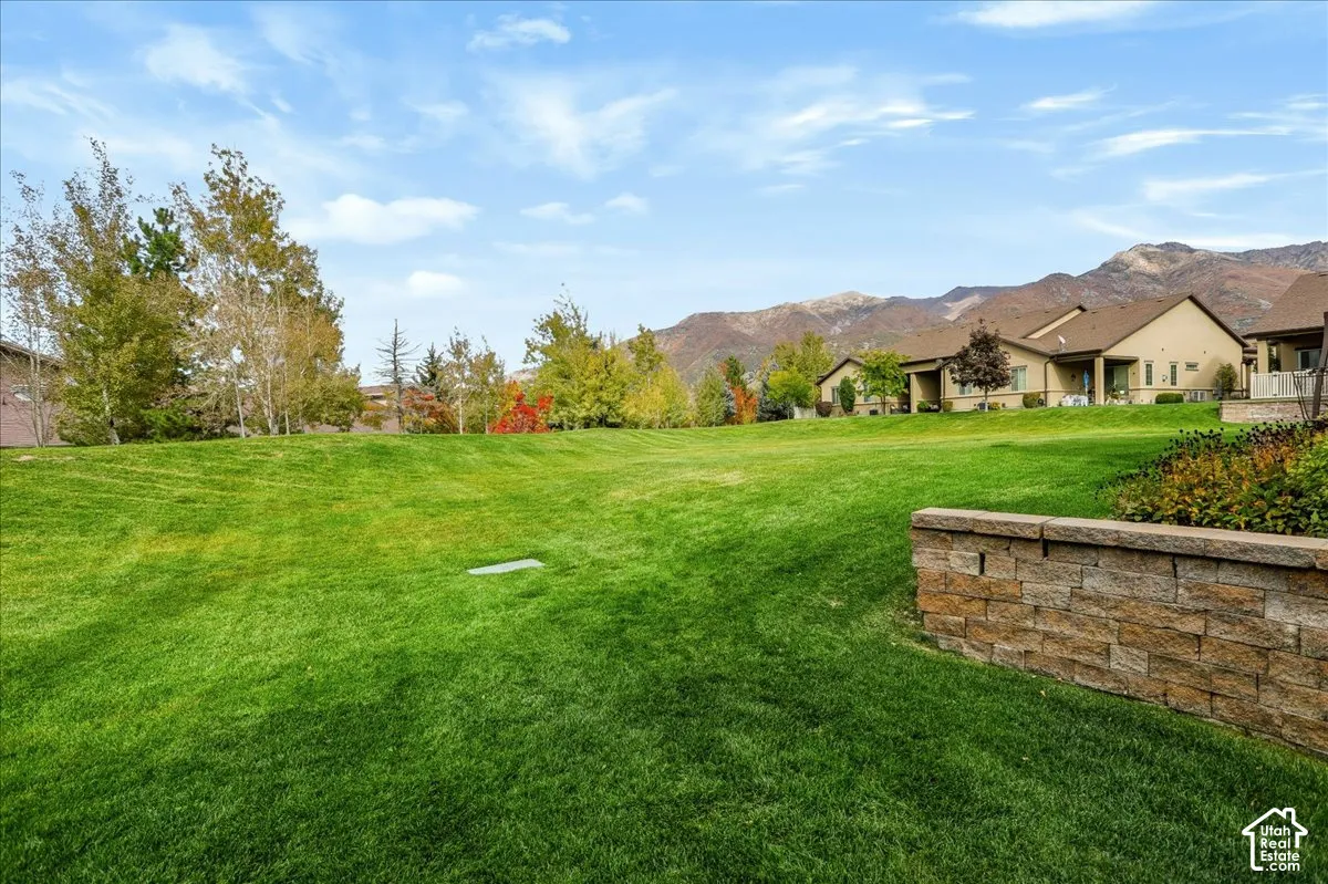 View from the pation of Expansive grass yard featuring a natural stone retaining wall and mountain backdrop