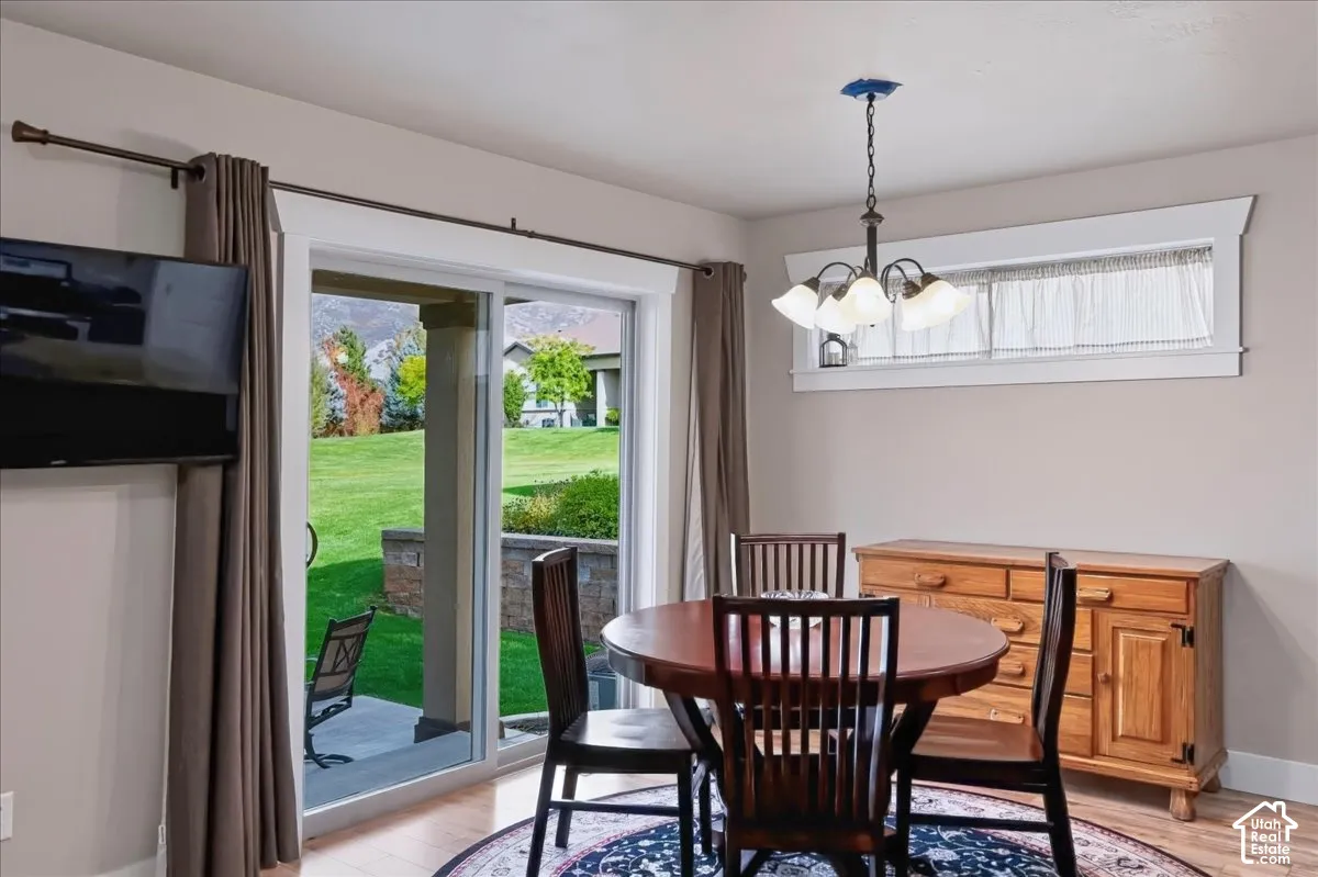 Sliding glass door to the patio, multi-light hanging chandelier, transom window, and wood-finish flooring