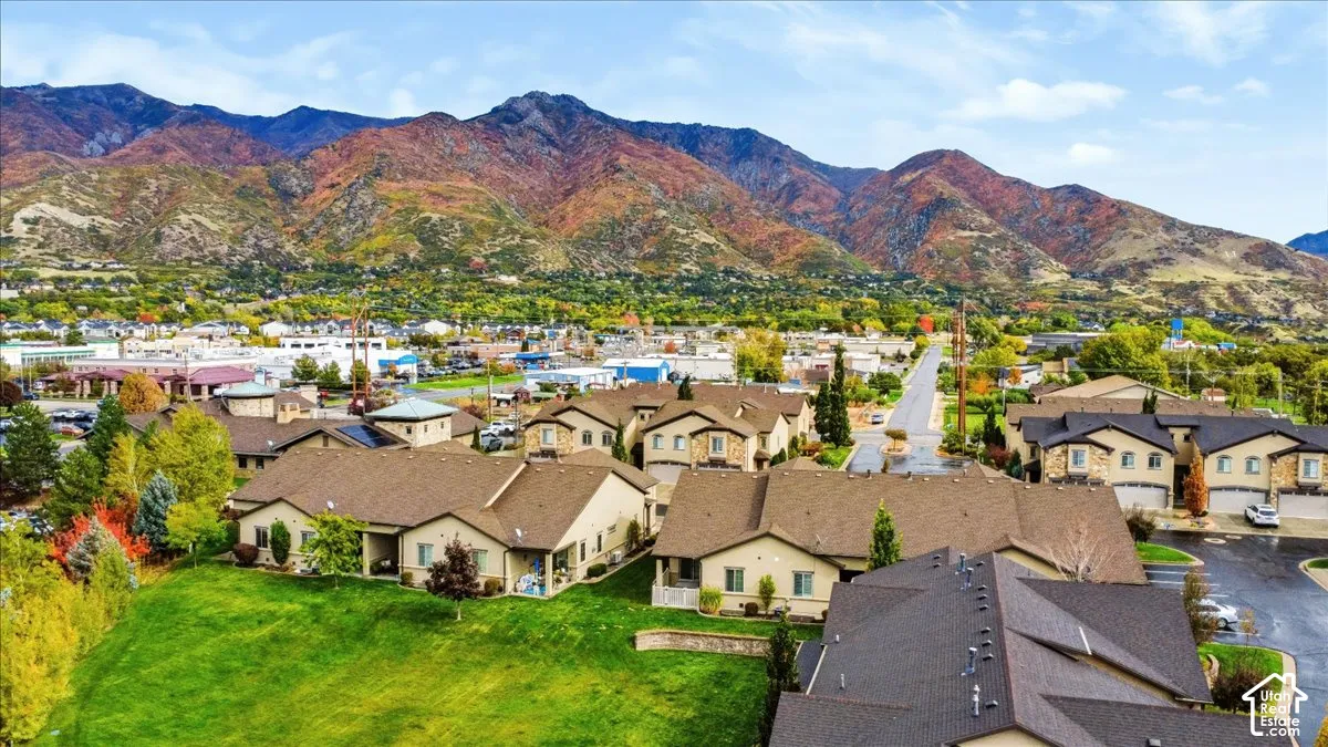 Aerial perspective of residential structures featuring multi-gable rooflines, stone and stucco siding, paved surface access, and mountain backdrop