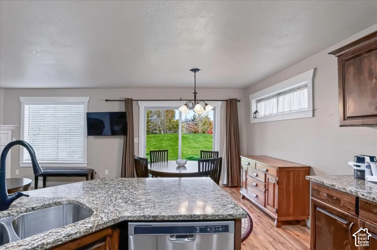 Kitchen featuring stone-finish countertops, stainless steel undermount sink, matte black faucet, wood-finish cabinetry, and glass sliding door access to exterior grounds