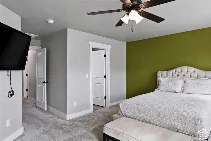 Primary Suite featuring neutral wall paint, a vibrant accent wall, wall-to-wall carpeting, and a ceiling fan with integrated lighting