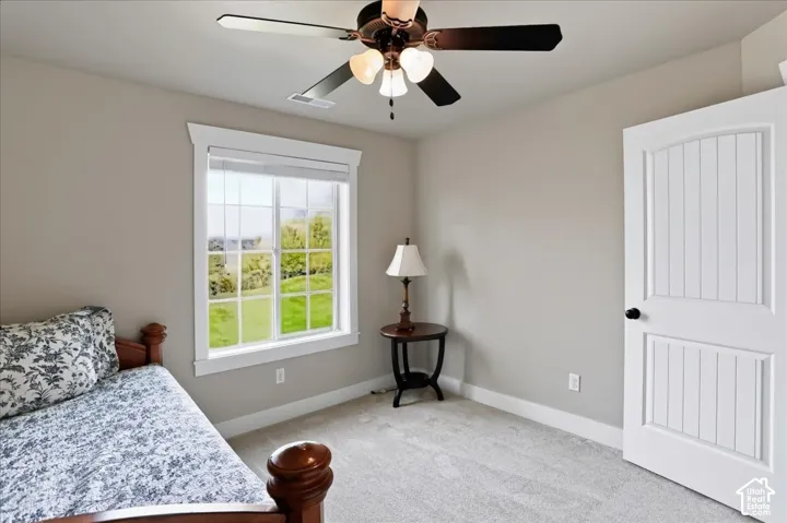Neutral-toned room featuring a multi-light ceiling fan, grid-patterned window with white trim, and a two-panel arched interior door
