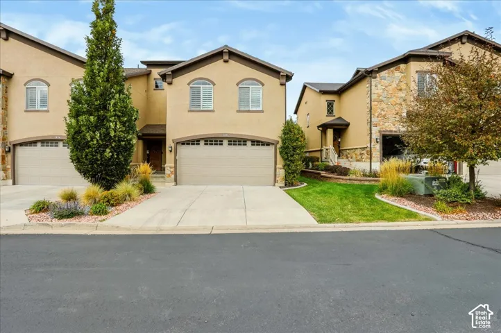 Tuscany Style Stucco exterior featuring arched window detailing, multi-car garage, and landscaped front yard with ornamental grasses