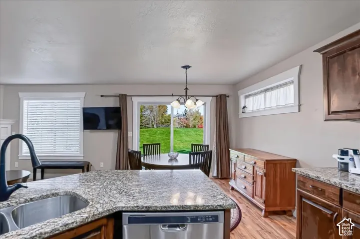 Kitchen featuring stone-finish countertops, stainless steel undermount sink, matte black faucet, wood-finish cabinetry, and glass sliding door access to exterior grounds