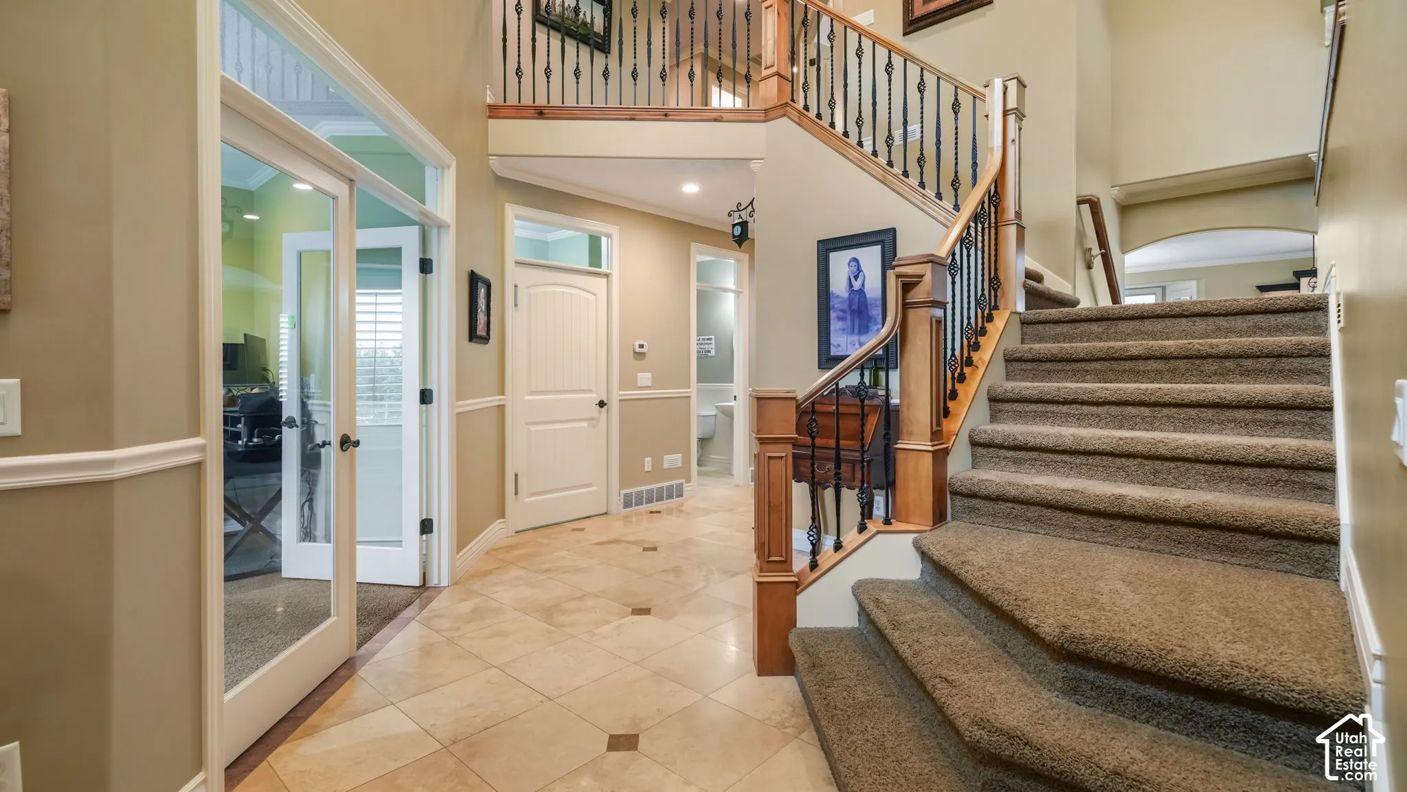Foyer featuring tile flooring, staircase with wood railings and metal balusters, and glass-paneled double doors