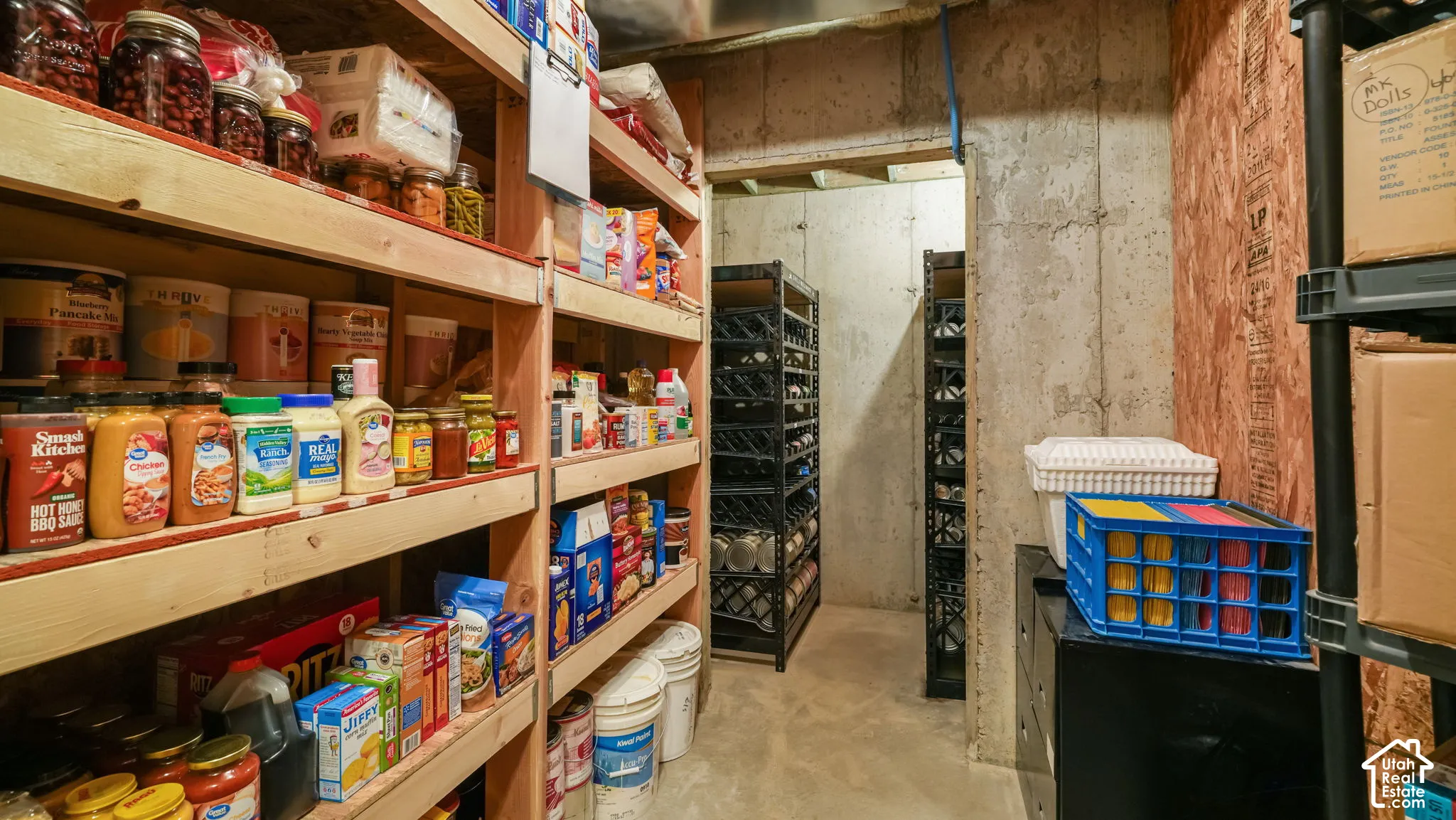 Storage area featuring exposed concrete walls and custom multi-level wood shelving