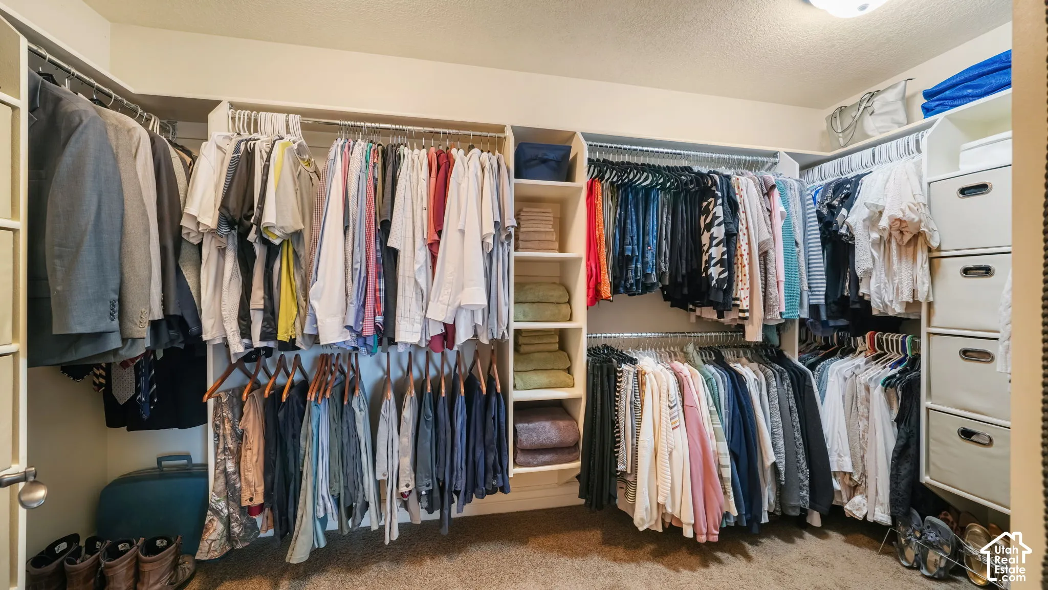 Walk-in closet featuring multi-level clothing rods, built-in open shelving, and four integrated pull-out drawers