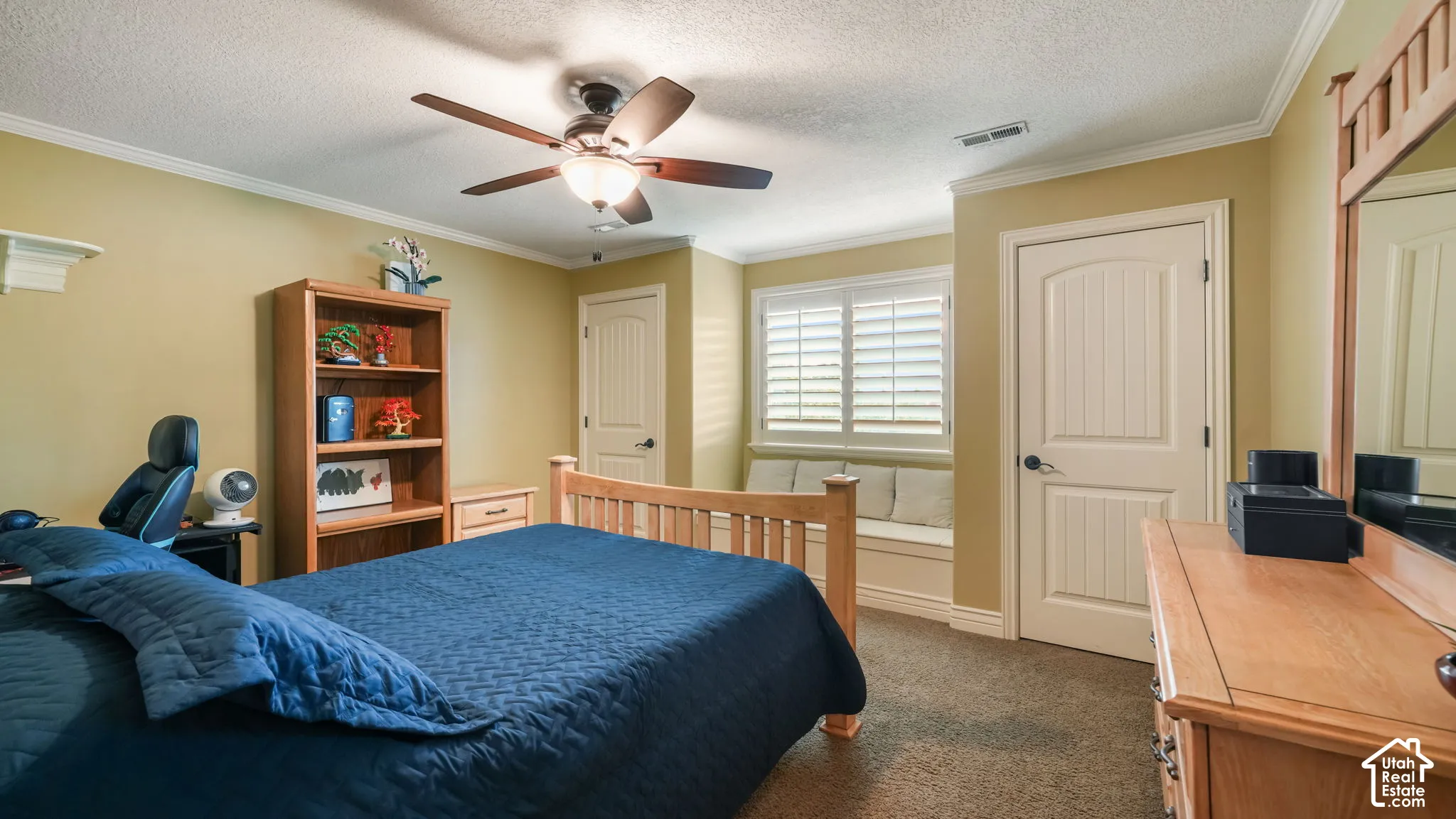 Built-in window seating with integrated cabinetry, plantation shutters, arched two-panel interior doors, and a ceiling fan with integrated light fixture
