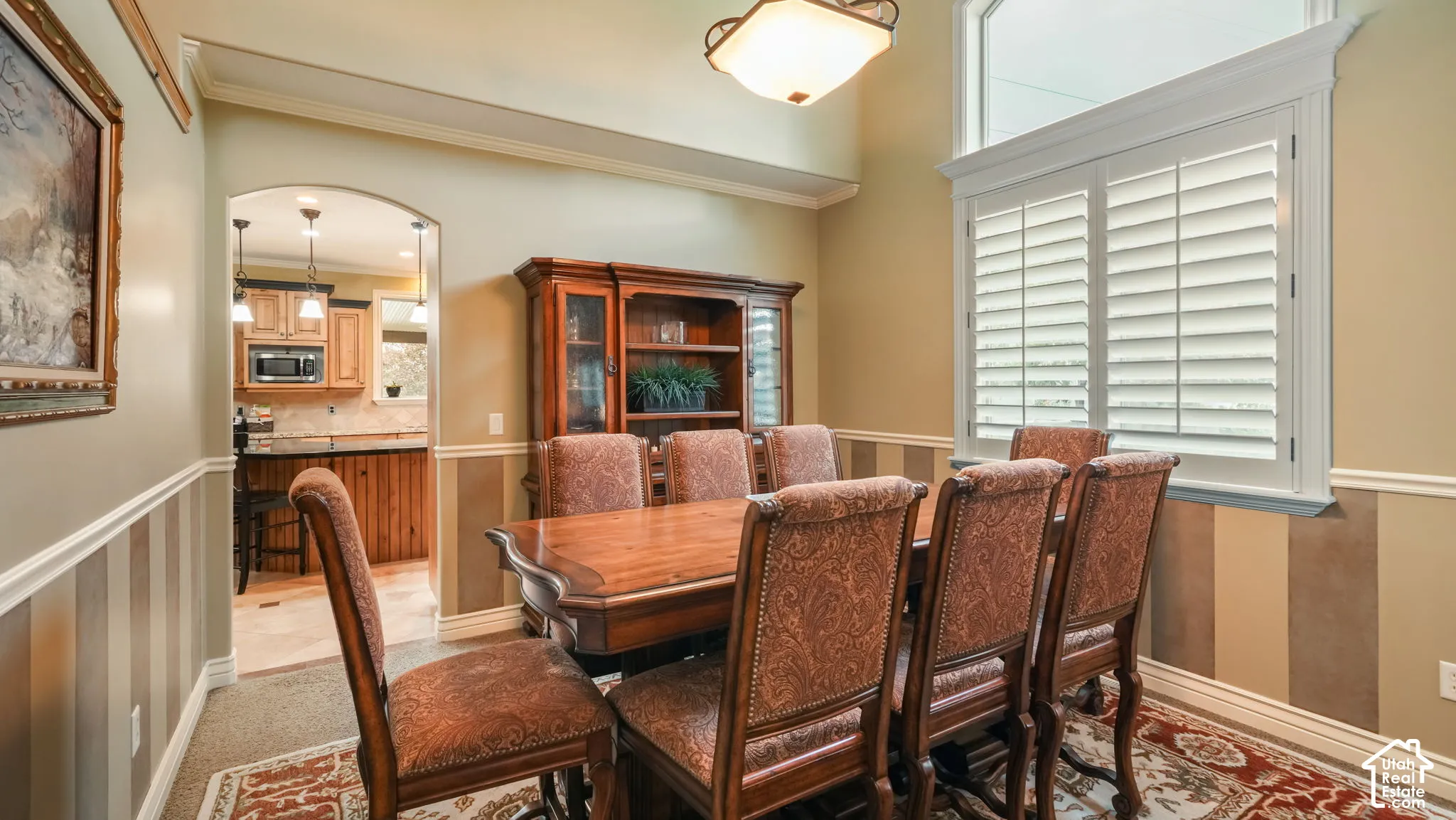 Vaulted ceiling with an arched window, plantation shutters, and crown molding