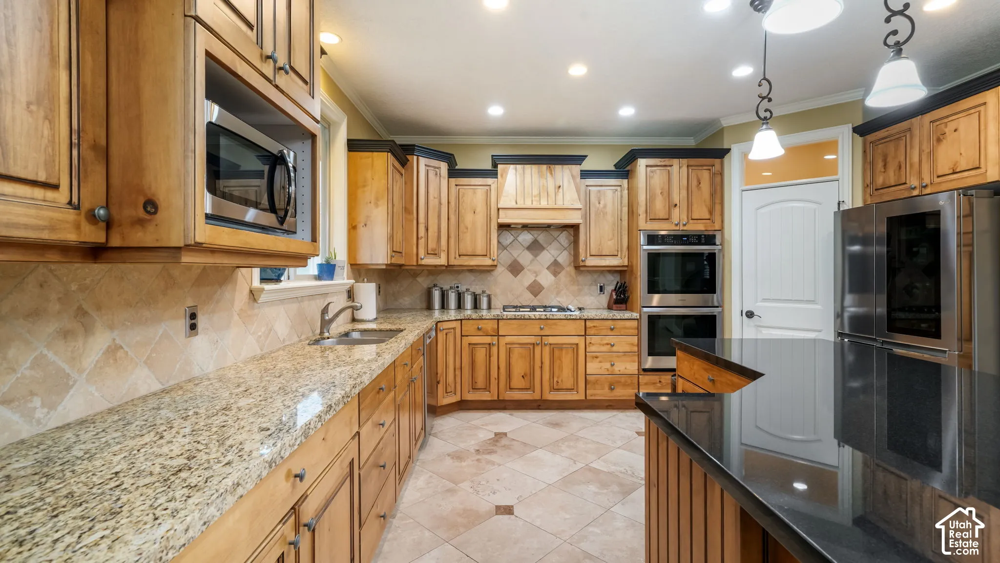 Kitchen featuring wood cabinetry, stone countertops, stone tile backsplash, stainless steel double wall ovens, and tile flooring