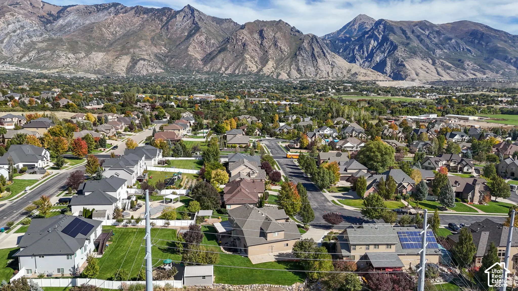 Aerial perspective of a residential neighborhood featuring mountain topography, mature trees, and varying roof pitches