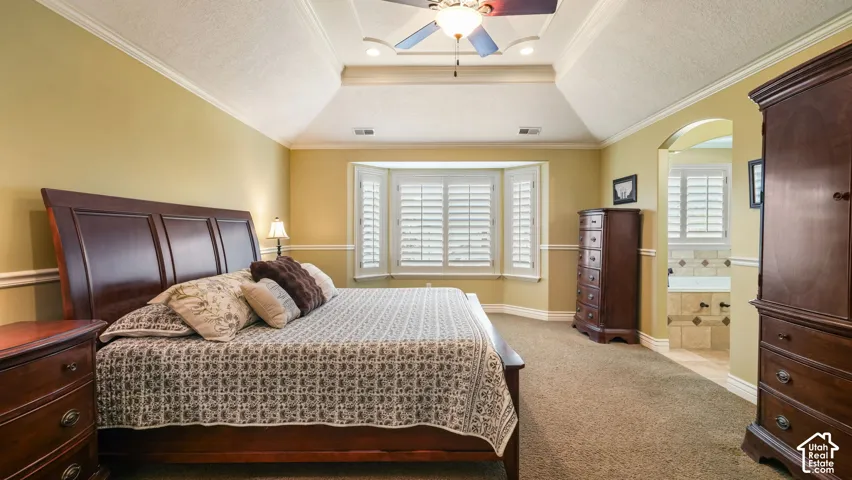 Tray ceiling with recessed lighting, bay window featuring plantation shutters, crown molding, and chair rail detailing