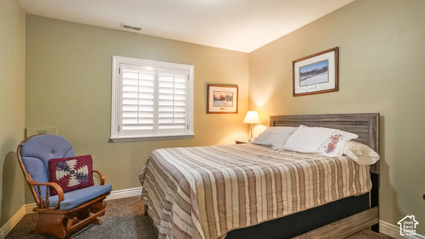 Neutral-toned interior space featuring white plantation shutters and wall-to-wall carpeting