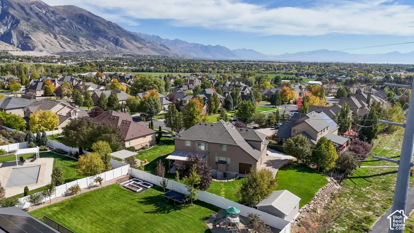 Aerial perspective showcasing mountain range backdrop, expansive manicured lawn, enclosed swimming pool, raised garden beds, and detached storage structure