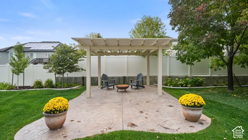 Backyard featuring a custom pergola, stamped concrete patio, manicured lawn, and perimeter privacy fencing