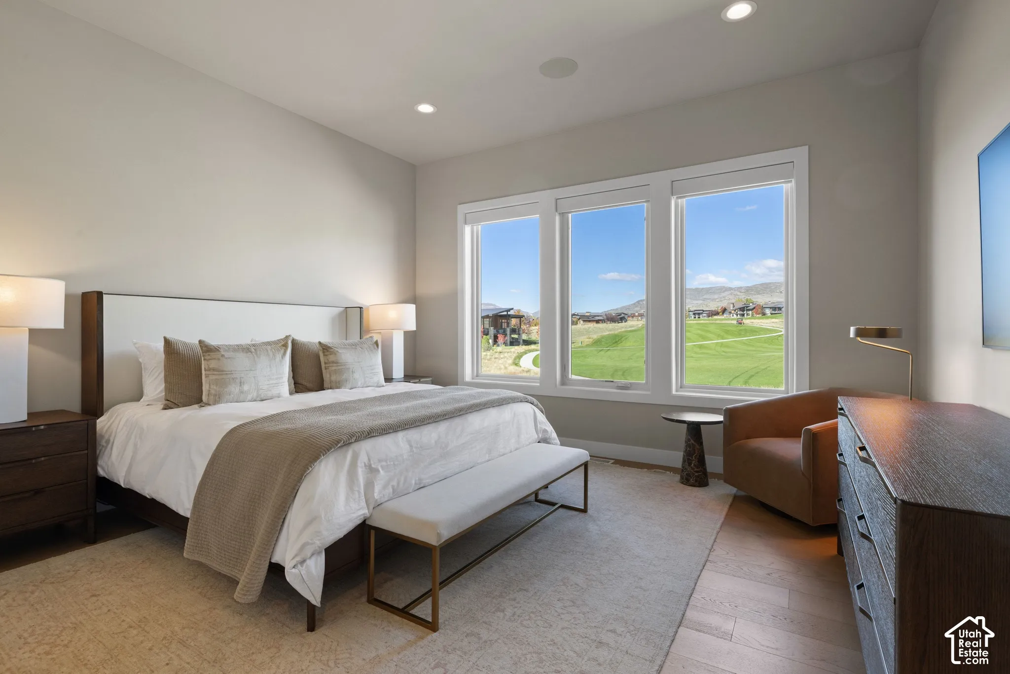 Room featuring wood-finish flooring, recessed lighting, and a triple window assembly with mountain and green space scenery