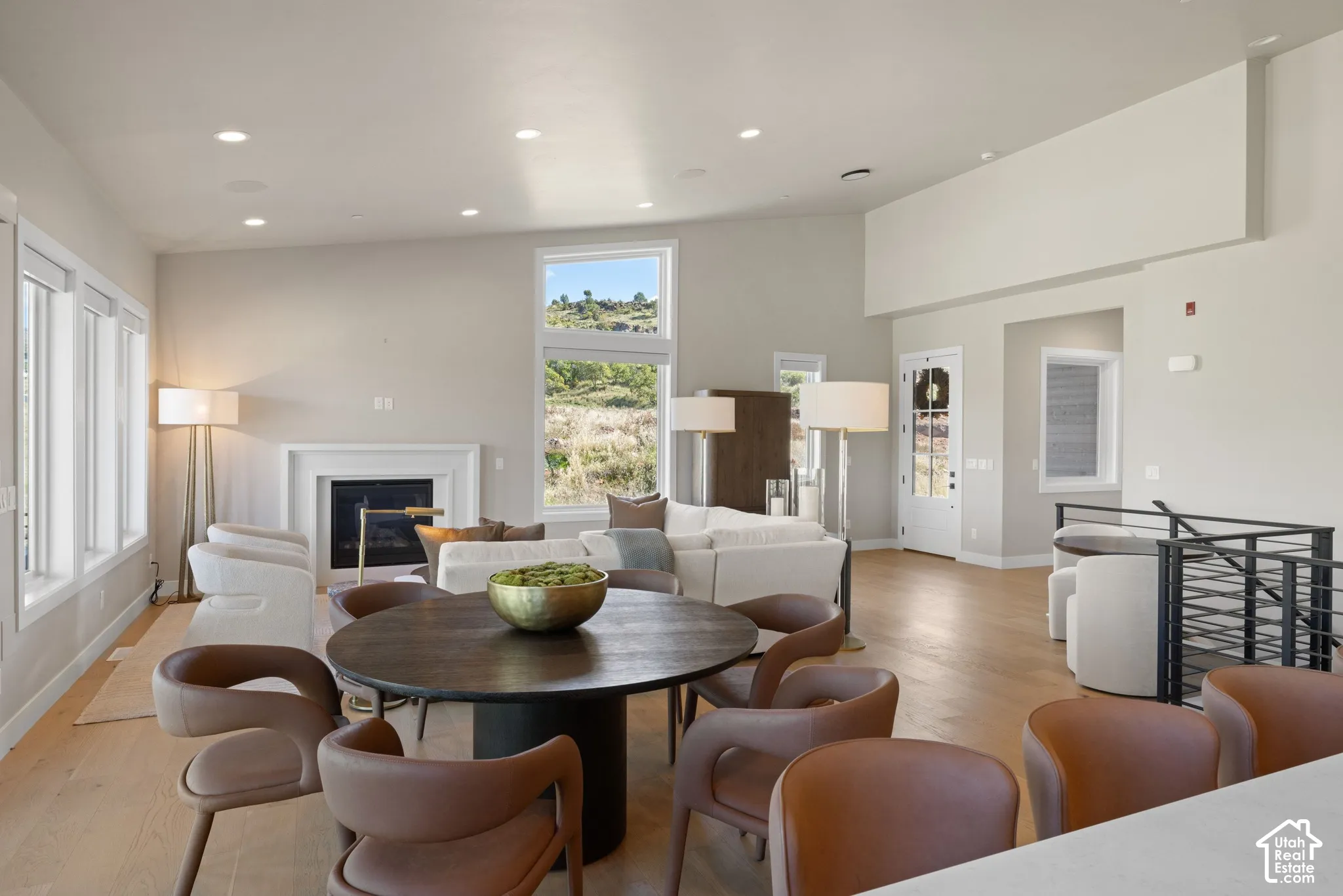 Open-concept living space featuring vaulted ceilings, recessed lighting, wood-finish flooring, a built-in fireplace with a clean-lined surround, and large windows